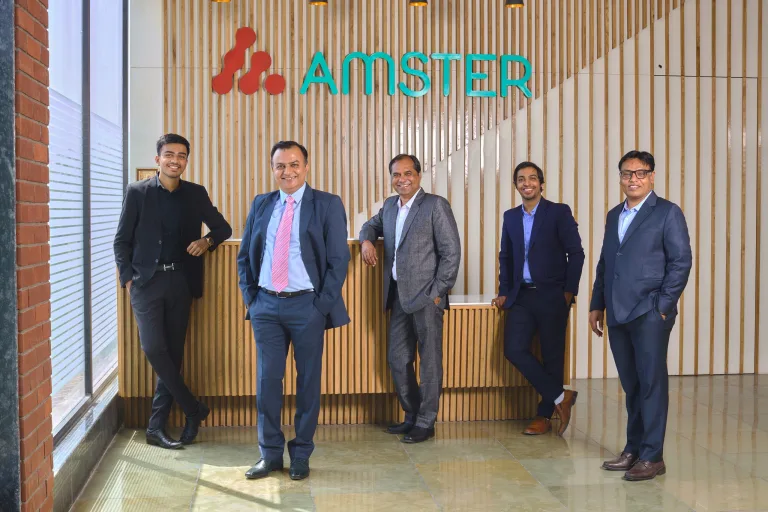 The Amster Microcell management team in reception, in front of the Amster sign