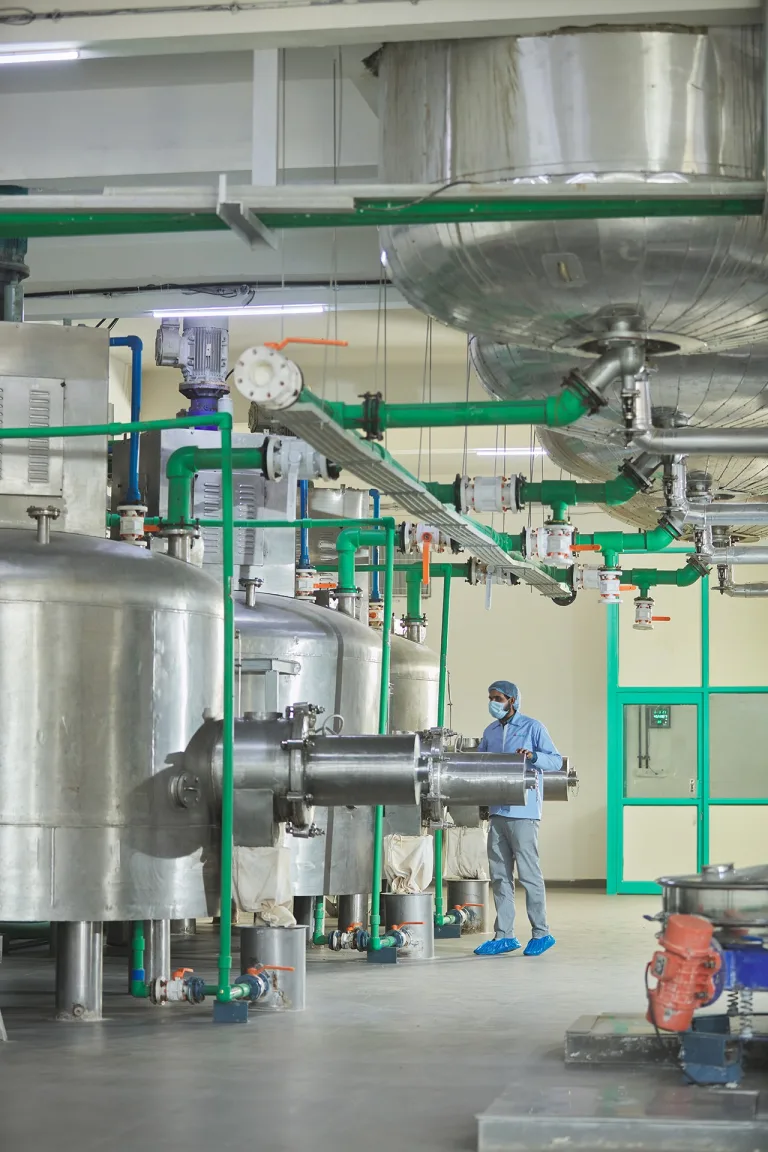 Stainless steel processing vessels and pipework, with an operator in protective clothing